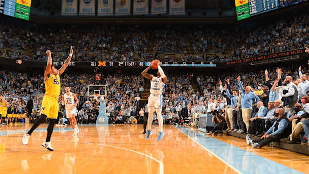 Dec 1, 2021; Chapel Hill, North Carolina, USA; North Carolina Tar Heels fans hold up three fingers as guard Caleb Love (2) shoots and Michigan Wolverines guard Eli Brooks (55) defends in the second half at Dean E. Smith Center. Mandatory Credit: Bob Donnan-USA TODAY Sports